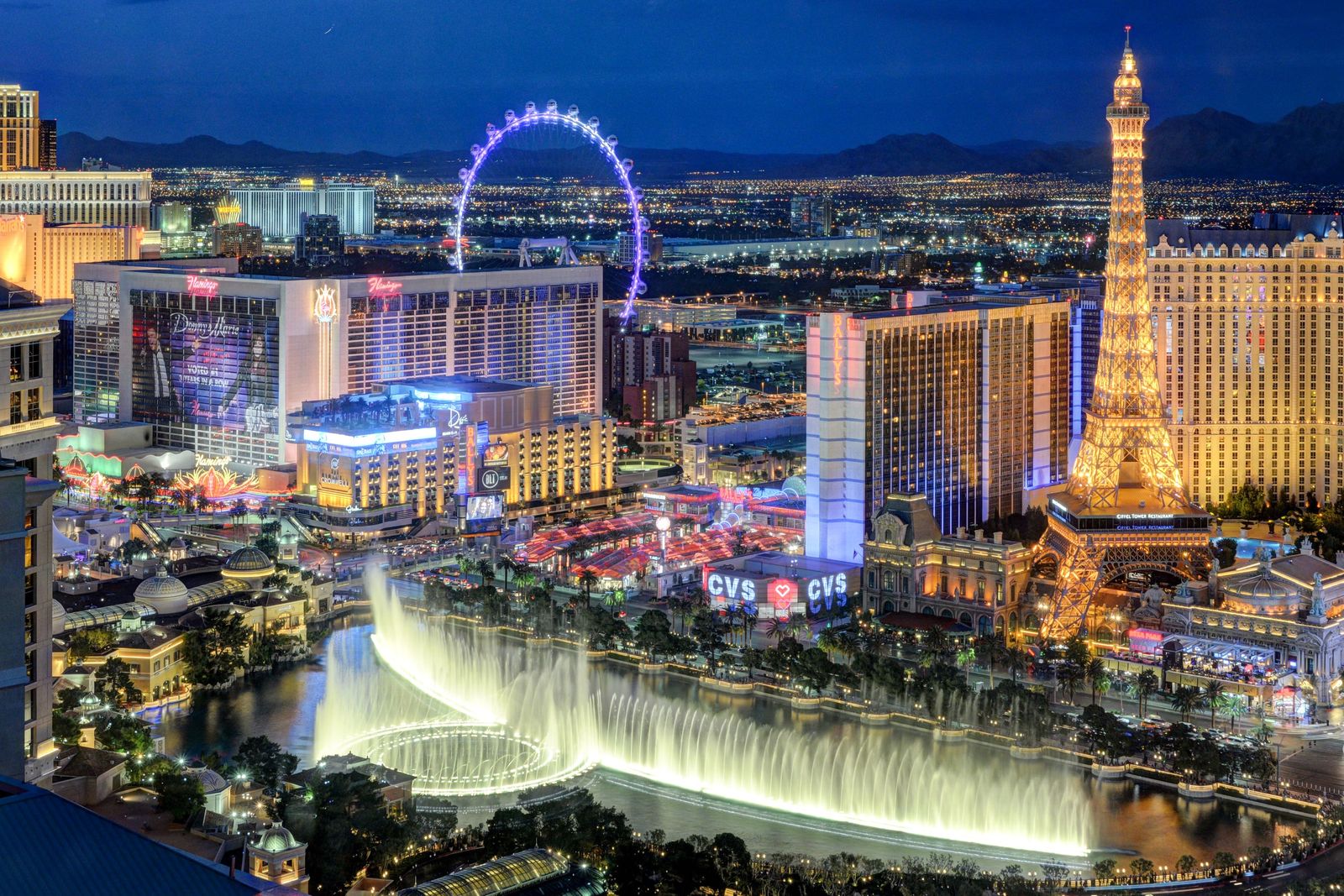 The Las Vegas Strip at night with an observation wheel, fountains and lit casino towers